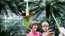 Allison Denny dan anaknya berfoto dengan latar belakang bunga bangkai raksasa Titan Arum di Botanic Garden, Washington, Amerika Serikat, Senin (2/8). Bunga bangkai raksasa dari Sumatera ini tak lama lagi akan mekar sempurna. (Zach GIBSON/AFP)