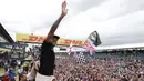 Pembalap Formula 1, Lewis Hamilton merayakan kemenangan bersama pengemarnya usai berlaga di Grand Prix Formula 1 Silverstone di Inggris, (5/7/2015). Hamilton berhasil finish di urutan pertama dengan waktu 1 jam 31 menit 27,729 detik. (Reuters/Hoch Zwei)