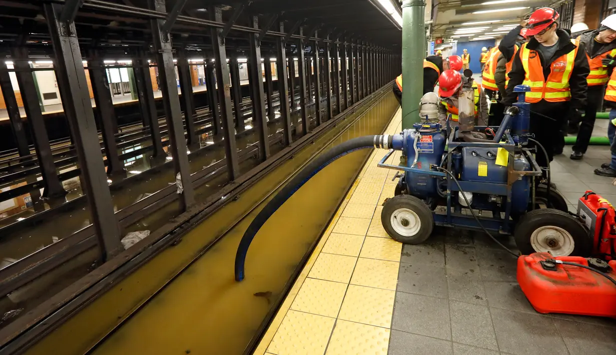 Para pekerja menyedot air dari stasiun kereta bawah tanah Lincoln Center yang banjir di New York, Amerika Serikat, Senin (13/1/2020). Genangan air menghambat layanan kereta bawah tanah pada jam sibuk. (AP Photo/Richard Drew)