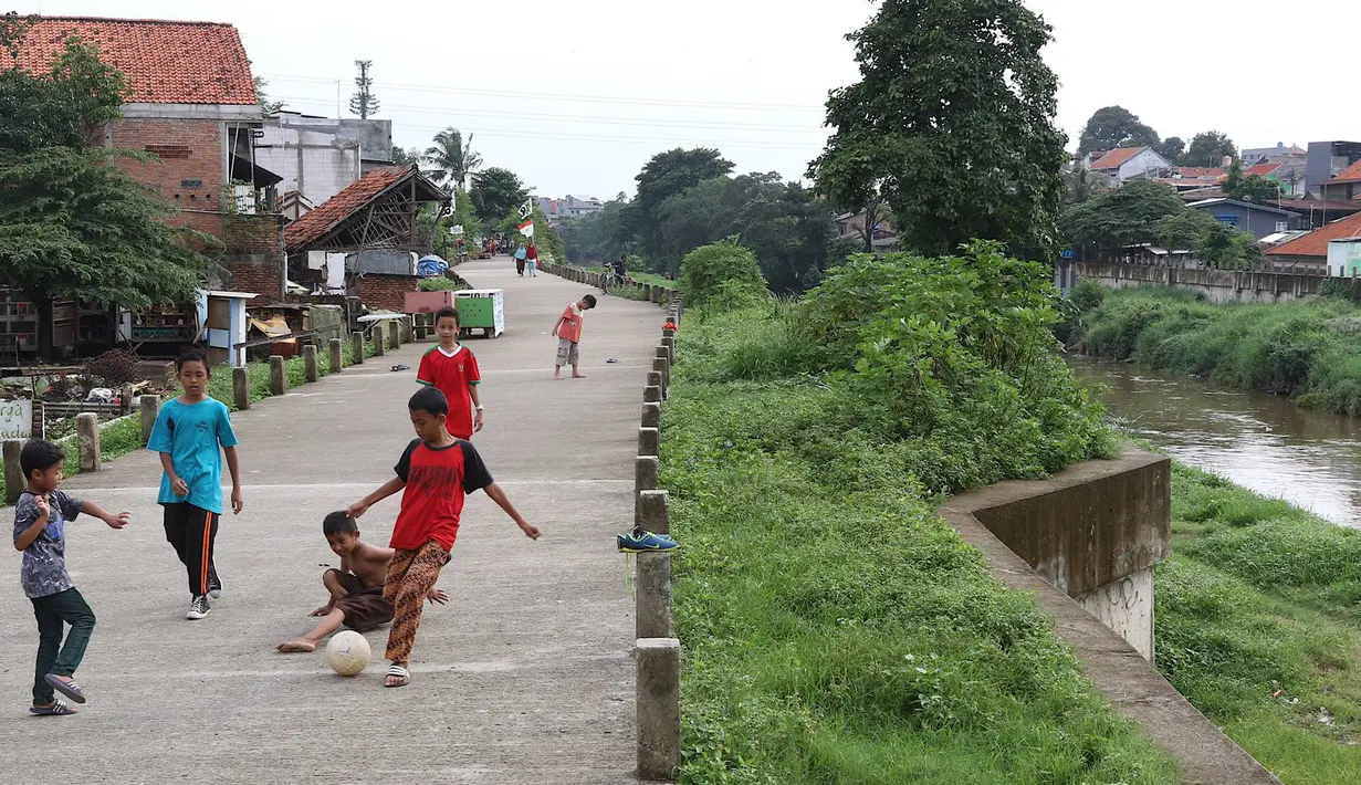 Anak-anak bermain sepak bola di jalur inspeksi Sungai Ciliwung di kawasan Rawajati, Jakarta, Rabu (23/1). Keterbatasan lahan tidak menyurutkan semangat mereka untuk bermain sepak bola meski di tempat seadanya. (Liputan6.com/Immanuel Antonius)