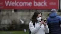 Seorang wanita mengenakan topeng untuk melindungi diri dari virus corona melihat ponselnya di Trafalgar Square, di London, Selasa (28/12/2021). Javid menuturkan, varian Omicron saat ini menyumbang sekitar 90 persen kasus baru di seluruh Inggris. (AP Photo/Alastair Grant)