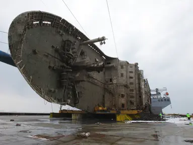 Petugas melintas didepan bangkai kapal Sewol yang berhasil diangkat di pulau barat daya Jindo, Korea Selatan (26/3). Kapal ini sebelumnya tenggelam hampir tiga tahun di kedalaman 44 meter. (HANDOUT / SOUTH KOREAN MARITIME MINISTRY / AFP)