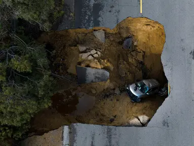 Foto drone memperlihatkan sebuah kendaraan terjebak dalam lubang runtuhan di Chatsworth, Los Angeles, California, Amerika Serikat, 10 Januari 2023. Serangkaian badai yang menghantam California telah menyebabkan jalanan terendam banjir, gelombang tinggi air laut, sungai meluap, dan memaksa ribuan orang untuk mengungsi. (AP Photo/Jae C. Hong)