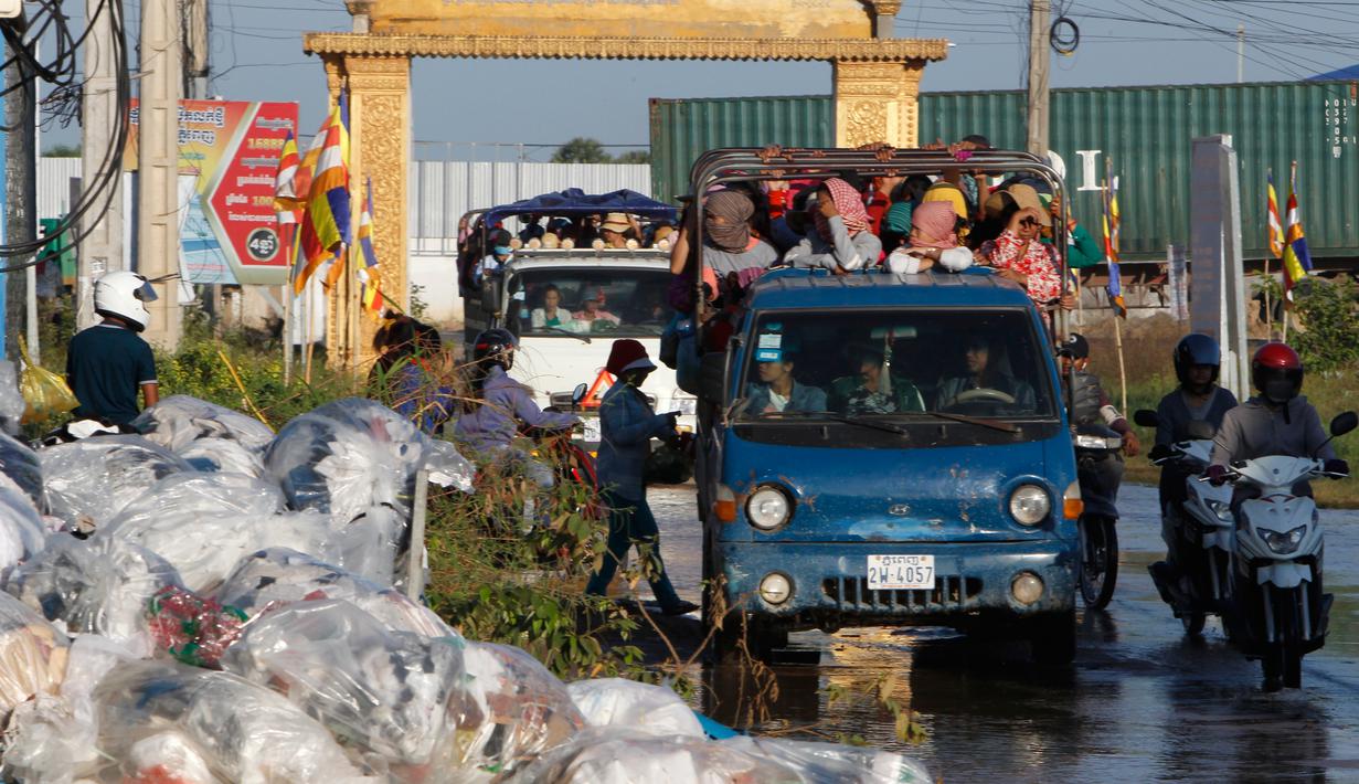 Dua mobil bak terbuka mengangkut para pekerja pulang ke rumah dari tempat kerja di sebuah pabrik di dekat desa Trapang Anchanh, di luar Phnom Penh, Kamboja (27/10). (AP Photo/Heng Sinith)