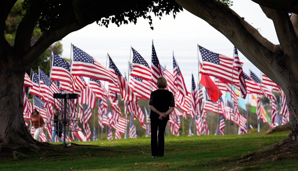 Seorang pengunjung melihat bendera Amerika Serikat (AS) untuk memperingati serangan teroris 11 September di halaman Universitas Pepperdine, Malibu, California, AS, Senin (11/9/2023). AS mengenang 22 tahun tragedi kelam serangan 11 September (9/11) di menara kembar World Trade Center (WTC), yang menewaskan nyaris 3.000 orang pada 2001. (AP Photo/Marcio Jose Sanchez)