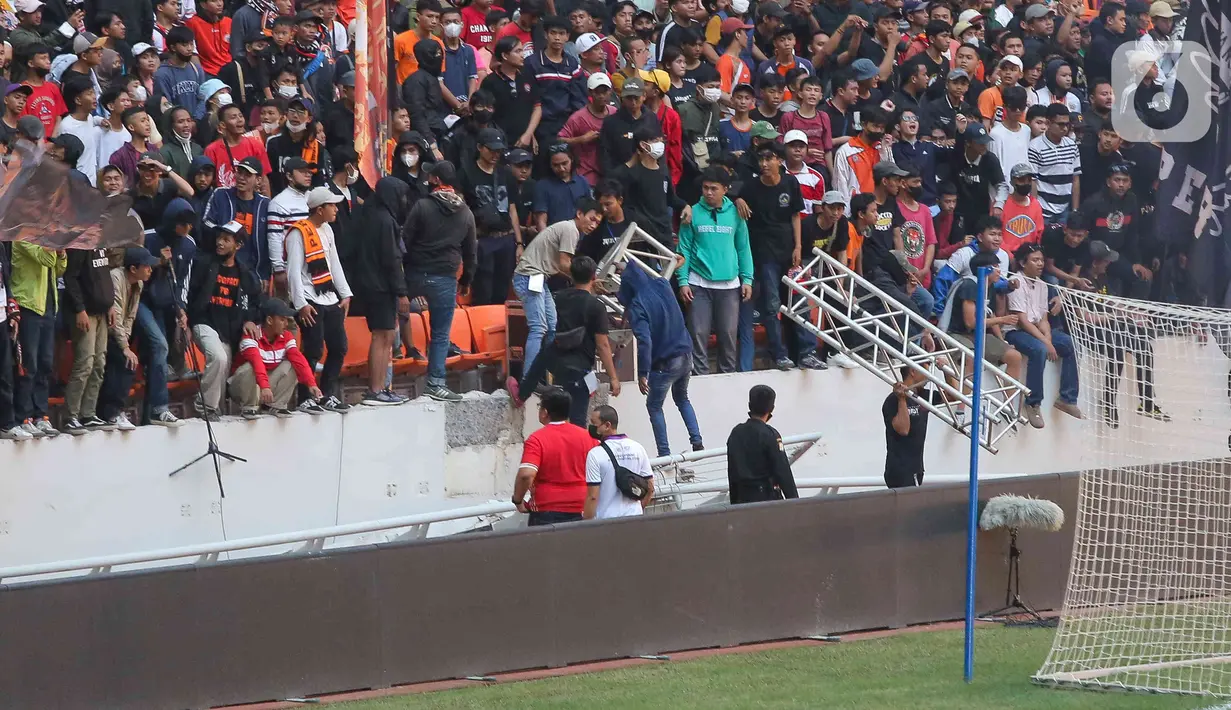 Sejumlah suporter berada di sekitar pagar besi tribun Jakarta International Stadium (JIS) yang rusak di Jakarta, Minggu (24/7/2022). Pagar di sisi utara stadion tingkat dunia tersebut roboh akibat diduduki oleh para penonton. (Liputan6.com/Herman Zakharia)