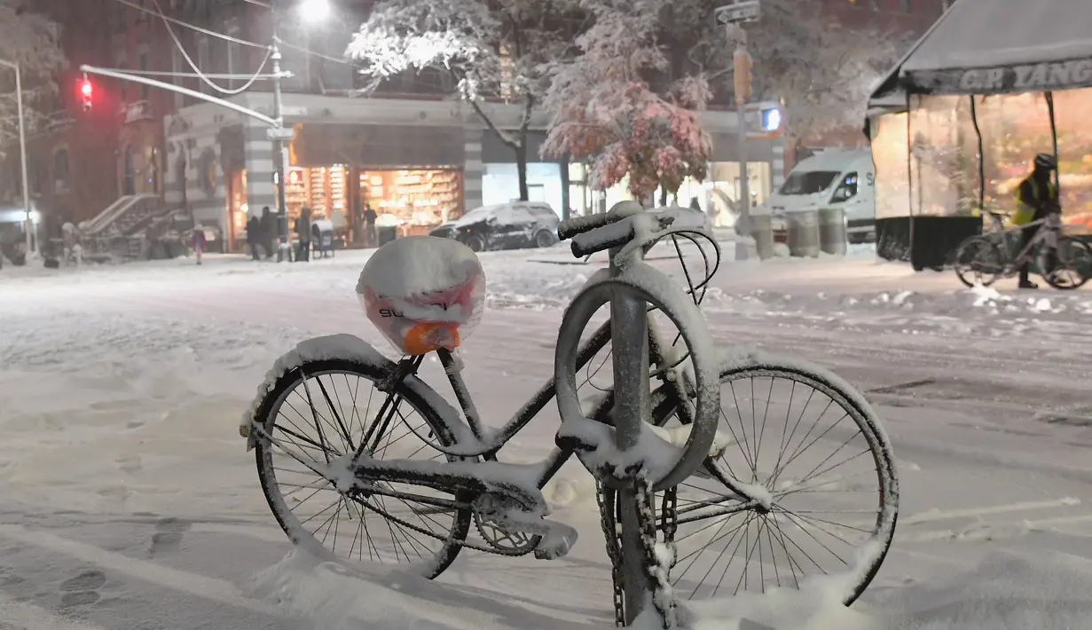 Sebuah sepeda tertutup salju terlihat di Manhattan, New York, Kamis (15/11). Layanan Cuaca Nasional memprediksi hujan salju pertama pada awal musim dingin itu akan mencapai ketebalan 2-4 inci. (Angela Weiss / AFP)