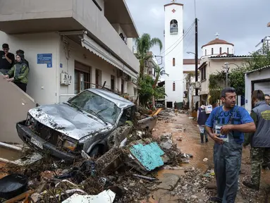 Warga mencoba membersihkan jalan dari puing-puing setelah hujan lebat di desa Malia, pulau Kreta, Yunani, Selasa (10/11/2020). Banjir besar di Pulau Kreta Yunani merusak jalan, membanjiri ratusan rumah, dan menyeret mobil ke laut di tengah hujan deras yang sedang berlangsung. (AP Photo/Harry Nakos)