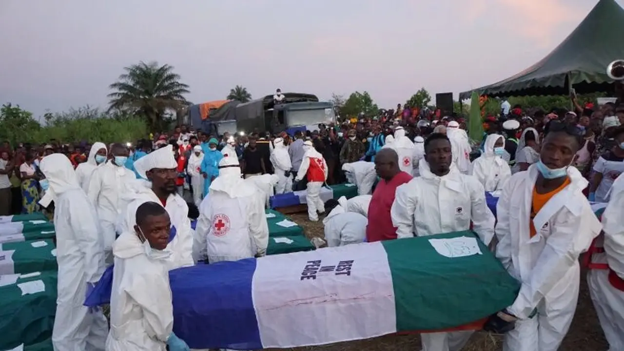 Petugas kesehatan membawa peti mati selama pemakaman 75 korban di Freetown pada 8 November 2021 di ibu kota Sierra Leone [Saidu Bah/ AFP].