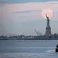 Bulan purnama terlihat di belakang Patung Liberty, New York City, Amerika Serikat, Kamis (7/5/2020). Fenomena supermoon atau di belahan Bumi lain disebut flower moon ini merupakan yang terakhir di tahun 2020. (Johannes EISELE/AFP)