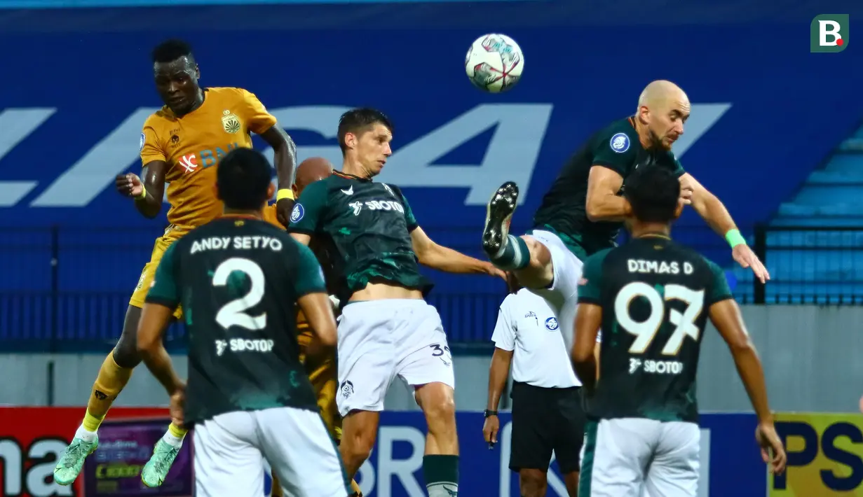 Pemain Bhayangkara FC, Ezechiel Ndouassel (kiri) melepaskan sundulan di depan dua pemain Persikabo 1973, Sergey Pushniakov (tengah) dan Shumeyko Veniamin dalam laga pekan ke-10 BRI Liga 1 2021/2022 di Stadion Moch. Soebroto, Magelang, Minggu (31/10/2021). (Bola.com/Nandang Permana)