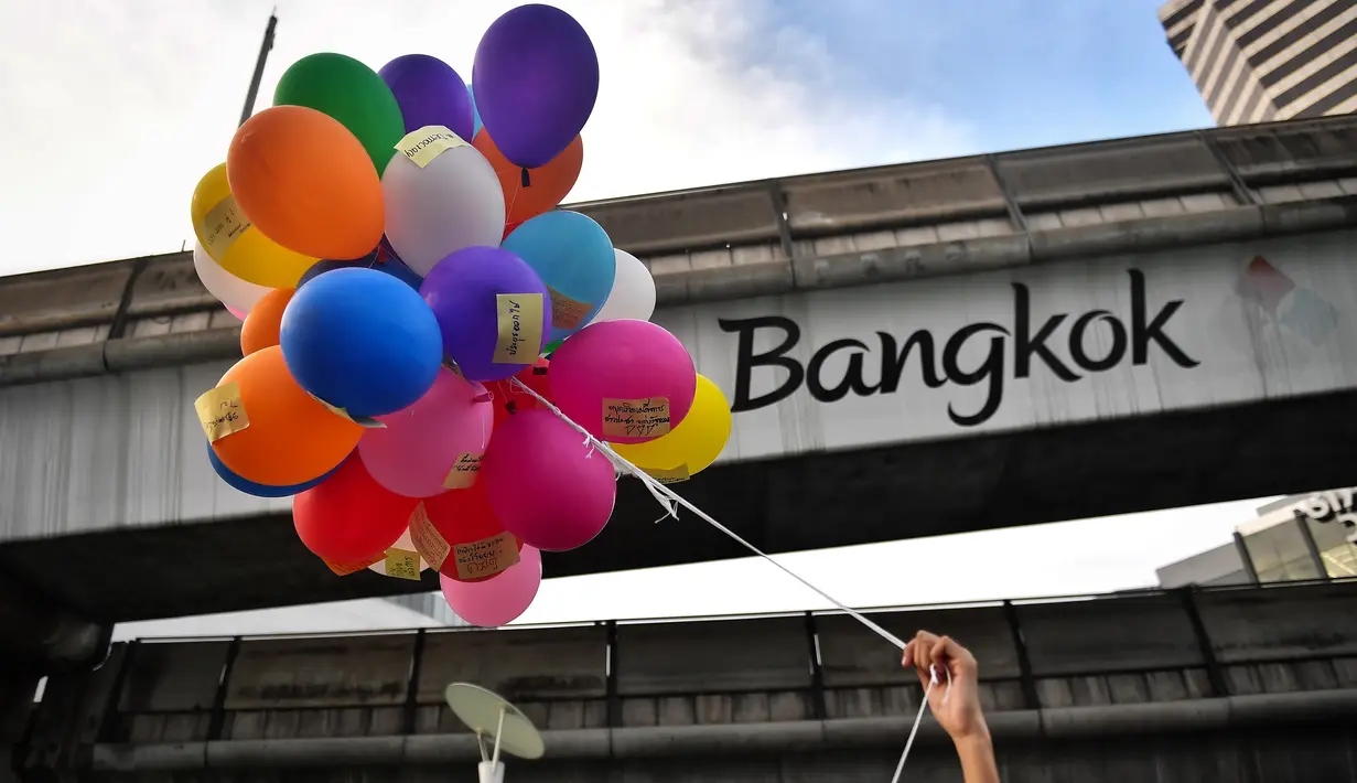 Seorang pengunjuk rasa memegang balon dengan pesan anti-pemerintah selama demonstrasi menentang usulan pembelian kapal selam oleh pemerintah yang berpihak pada militer di Bangkok (31/8/2020). (AFP/Lillian Suwanrumpha)