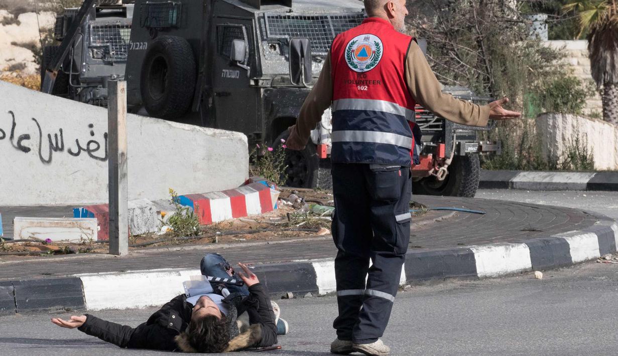 Seorang pria Palestina terjatuh usai ditembak dari jarak dekat oleh polisi Israel di dekat Ramallah, Tepi Barat, Jumat (15/12). Pemuda ini ditembak usai menikam tentara perbatasan Israel. (AFP Photo/Oren Ziv)