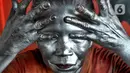 Pagi jelang siang pada  sudut toko perempatan lampu merah,  Nenek Mumum mulai merias wajah dan tubuhnya dengan cat silver. (merdeka.com/Arie Basuki)