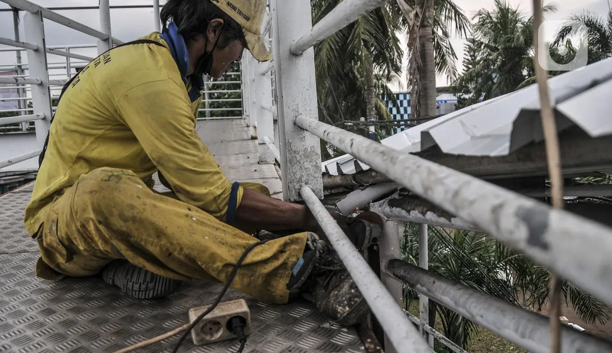 Petugas Sudin Bina Marga Jakarta Timur memperbaiki jembatan penyeberangan orang (JPO) di Jalan Otto Iskandardinata (Otista), Jatinegara, Rabu (9/2/2022). Perbaikan JPO itu tindak lanjut pasca insiden tertimpa pohon tumbang pada November tahun lalu akibat cuaca ekstrem. (merdeka.com/Iqbal S Nugroho)