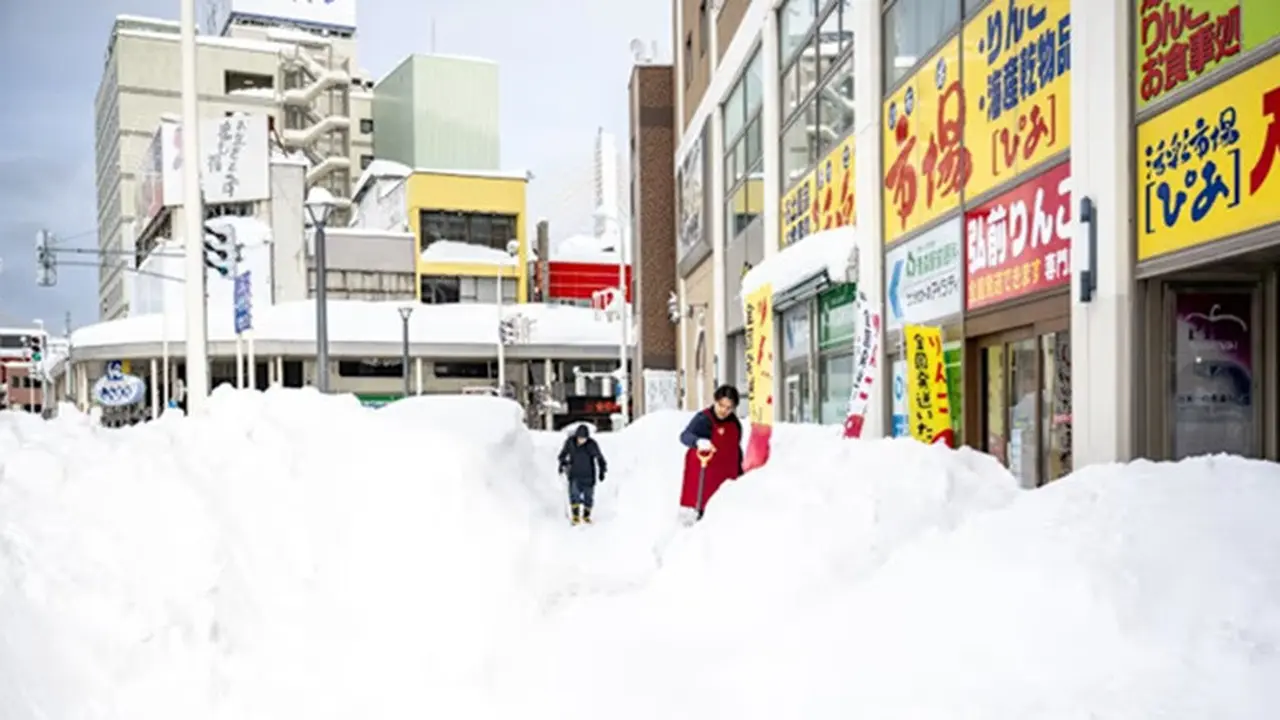 Seorang pejalan kaki melintasi persimpangan jalan yang tertutup salju di Kota Aomori, Prefektur Aomori, pada Jumat (30/1/2026).