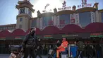 Wisatawan yang mengenakan masker untuk melindungi dari penyebaran virus corona berjalan dengan membawa barang bawaan mereka di Stasiun Kereta Api Beijing di Beijing, Kamis (28/1/2021).  Upaya untuk mencegah warga Tiongkok bepergian untuk Tahun Baru Imlek tampaknya berhasil. (AP Photo/Mark Schiefelb
