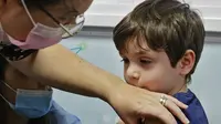 Bocah Israel, Itamar (5) disuntik dosis vaksin Covid-19 Pfizer/BioNTech Covid-19 di Meuhedet Healthcare Services Organization di Tel Aviv, saat Israel memulai kampanye vaksinasi virus corona untuk anak berusia 5 hingga 11 tahun, Senin (22/11/2021). (JACK GUEZ / AFP)