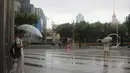 Warga berdiri dengan payung di tengah hujan saat Topan In-fa menyapu Shanghai di China (25/7/2021). Di kota Zhengzhou, upaya penyelamatan terus berlanjut dan bantuan logistik diangkut dengan truk untuk kemudian disalurkan kepada korban banjir. (AP Photo/Chen Si)