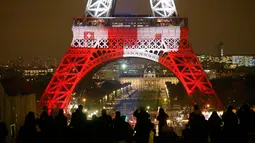 Wisatawan mengambil gambar Menara Eiffel pada Senin (16/11), yang dihiasi lampu berwarna bendera Prancis untuk menghormati para korban serangan teror di Paris hari Jumat (13/11) lalu. (REUTERS/Benoit Tessier)