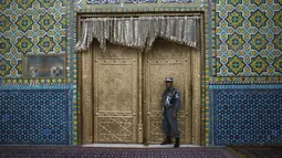 Seorang polisi di gerbang Hazrat-e-Ali atau Masjid Biru di Mazar-e-Sharif, Afghanistan, Rabu (7/7/2021). Masjid Biru adalah tempat yang diminati orang-orang untuk menikmati ketenangan dari hiruk jalanan dan keramaian aktivitas pasar. (AP Photo/Rahmat Gul)