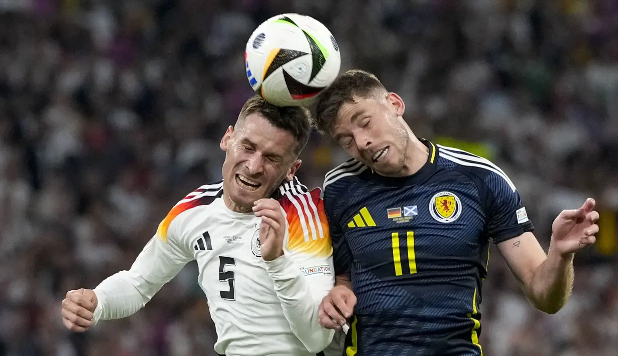 Pemain Jerman, Pascal Gross (kiri) berduel udara dengan pemain Skotlandia, Ryan Christie pada laga pembuka Grup A Euro 2024 di Allianz Arena, Munchen, Jerman, Sabtu (15/06/2024) WIB. (AP Photo/Antonio Calanni)