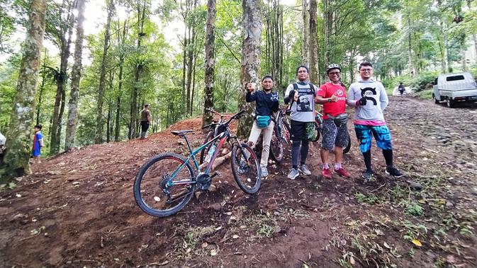 Para penunggang sepeda gunung tengah bersandar menikmati treck kawasan wisata alam Curug Candung, di tengah hutan pinus. (Liputan6.com/Jayadi Supriadin)