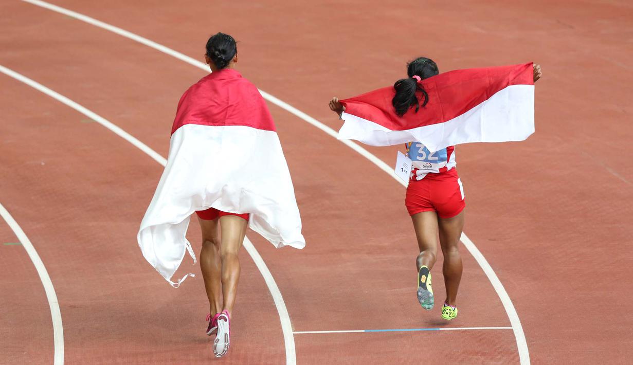 Selebrasi putri Indonesia, Rini Budiarti (kiri) yang meraih medali perak dan Triyaningsih meraih emas nomor lari 5.000m SEA Games 2015. (Bola.com/Arief Bagus)