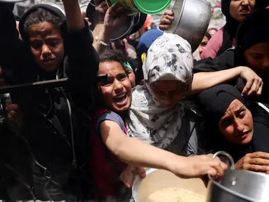 Warga Palestina berjuang untuk mendapatkan jatah makanan mereka di luar pusat distribusi di Beit Lahia, Jalur Gaza Utara pada 15 Mei 2025. (BASHAR TALEB/AFP)