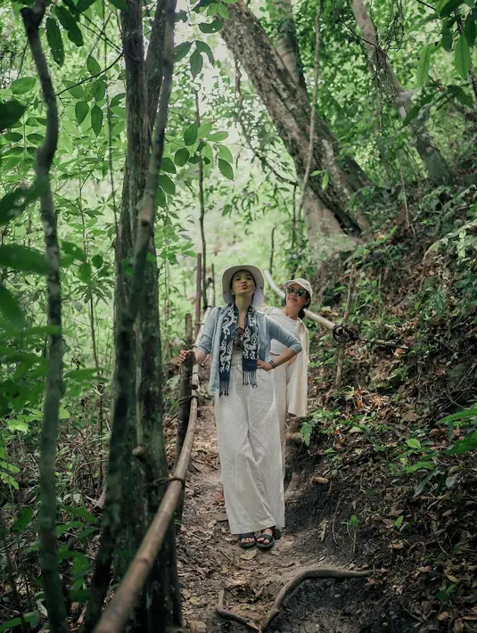 Raline Shah kenakan outfit serba panjang saat tracking di hutan. Ia mengenakan outer biru dengan loose pants linen dan syal tenun Sumba biru navy. Lengkap dengan topi bundar di atas kepala. [@ralineshah]