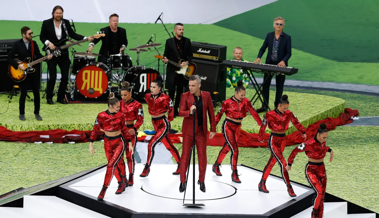 Penampilan penyanyi Inggris, Robbie Williams pada upacara pembukaan Piala Dunia 2018 di Stadion Luzhniki, Moskow, Kamis (14/6). Robbie dikelilingi para penari dengan atasan berkilauan merah terang yang menambah meriah penampilan. (AP/Darko Bandic)