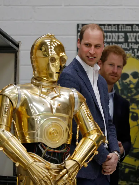 Pangeran William dan Harry melihat C3P0 droid saat mengunjungi studio pembuatan film Star Wars di Pinewood Studios, London, (19/4). Pangeran Inggris itu berkeliling Pinewood untuk mengunjungi workshop produksi film Star Wars (REUTERS/Adrian Dennis/Pool)