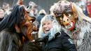 Seorang wanita berfoto bersama peserta yang mengenakan kostum iblis saat parade tardisional Perchtenlauf di Osterseeon dekat Munchen, Jerman (17/12). (Reuters/Michaela Rehle)