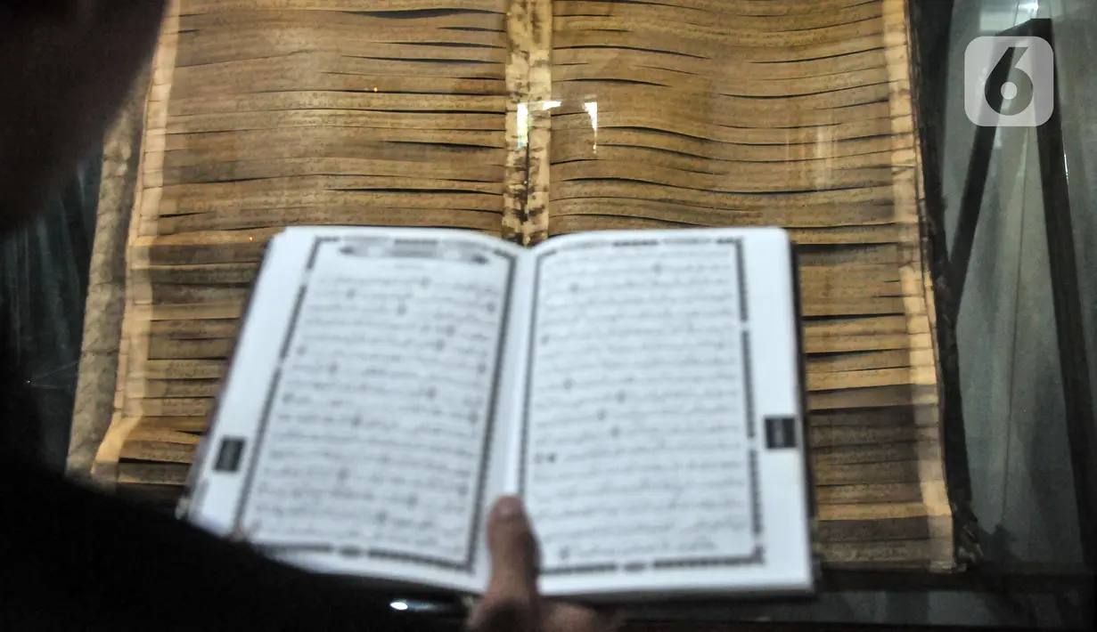 Pengurus mencocokkan penggalan ayat Alquran raksasa dengan Alquran cetakan terkini. (merdeka.com/Iqbal S. Nugroho)