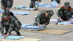 Mahasiswa baru belajar melipat selimut selama sesi pelatihan militer di sebuah kampus di Yangzhou, Jiangsu, China, Jumat (6/9/2019). Pelatihan militer bagi mahasiswa baru di China  biasanya dilakukan pada akhir liburan musim panas. (STR/AFP)