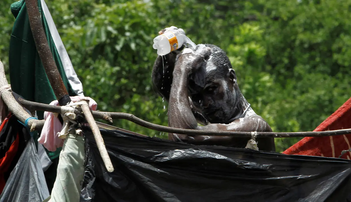 Seorang pria migran Afrika yang terdampar di Kosta Rika saat mandi di sebuah kamp darurat di perbatasan antara Kosta Rika dan Nikaragua, di Penas Blancas, Kosta Rika, (14/7). (REUTERS / Juan Carlos Ulate)