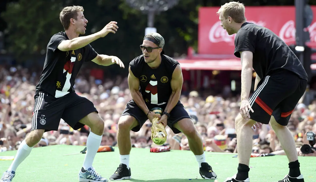 Tiga penggawa Timnas Jerman, Thomas Mueller, Lukas Podolski dan Per Mertesacker (kiri ke kanan), bercanda di atas panggung saat perayaan kemenangan di Berlin, (15/7/2014). (REUTERS/Alex Grimm/Pool)