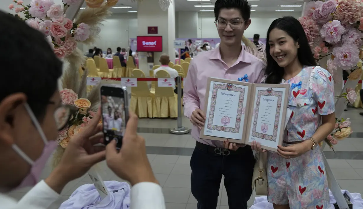 Petugas mengambil gambar pasangan dengan akta pernikahan mereka pada Hari Valentine di distrik Bang-Rak, Bangkok, Thailand, Senin (14/2/2022). Banyak pasangan menikah pada saat ini lokasi karena mereka percaya nama keberuntungannya akan membawa cinta yang tahan lama. (AP Photo/Sakchai Lalit)