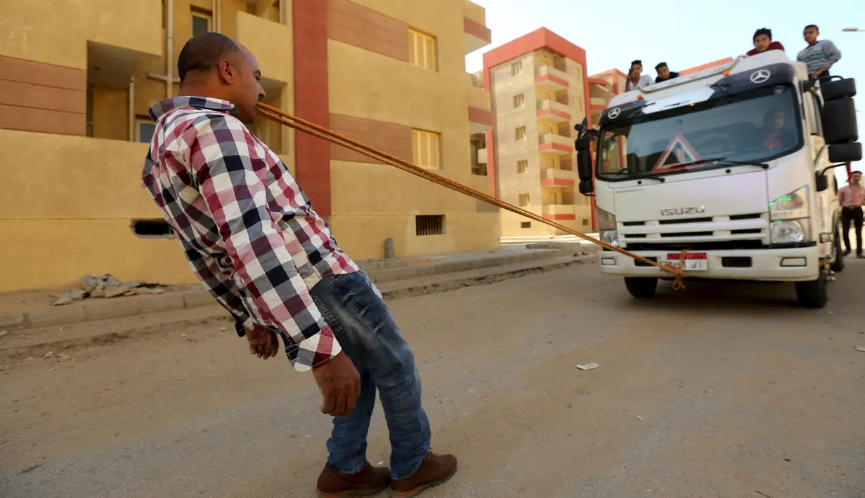 Karim Hussein menarik truk dengan gigi saat unjuk kebolehan di Kairo (18/3/2016). Berkat aksinya tersebut, Karim mendapat julukan "The Pharaoh" dan dinobatkan sebagai pria terkuat di Mesir. (Reuters/ Mohamed Abd El Ghany)