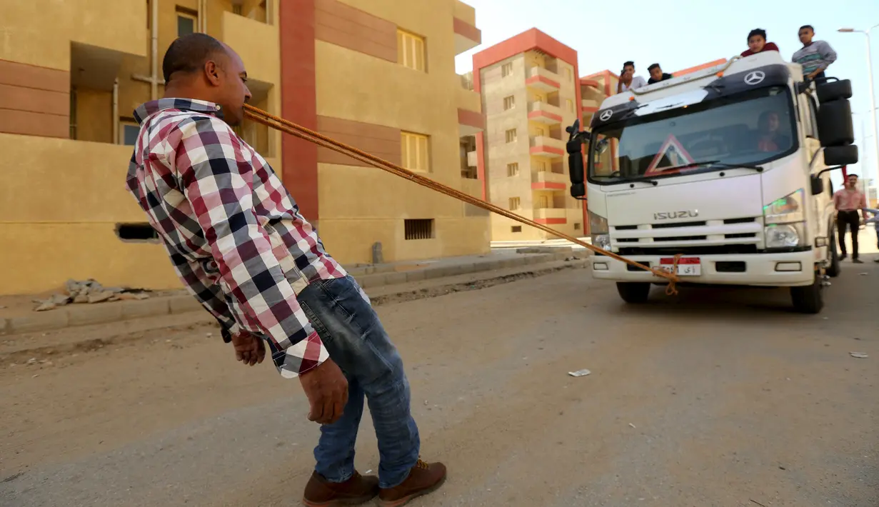 Karim Hussein menarik truk dengan gigi saat unjuk kebolehan di Kairo (18/3/2016). Berkat aksinya tersebut, Karim mendapat julukan "The Pharaoh" dan dinobatkan sebagai pria terkuat di Mesir. (Reuters/ Mohamed Abd El Ghany)
