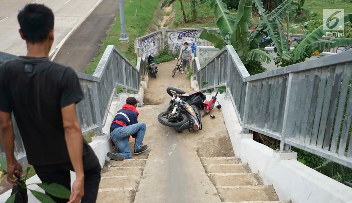 Pengendara sepeda motor terjatuh saat melintasi JPO yang melintang di atas Tol Cijago Seksi II di Depok, Jawa Barat, Rabu (15/5). Meskipun berbahaya, namun curamnya akses JPO tidak menjadi penghalang bagi pemotor untuk menyeberang agar memersingkat waktu tempuh. (Liputan6.com/immanuel Antonius)