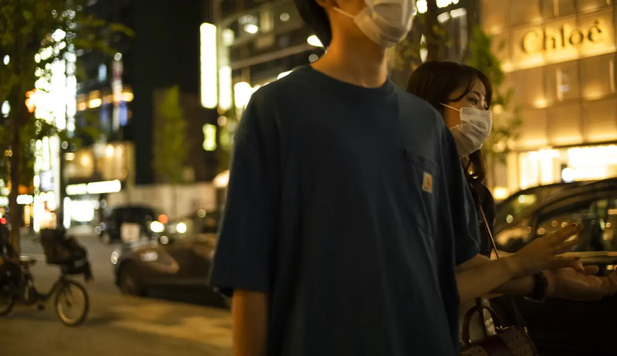 Seorang pria dan seorang wanita mengenakan masker berjalan di sepanjang jalan di distrik perbelanjaan Ginza Tokyo, Kamis (23/9/2021). Ginza dikenal sebagai salah satu pusat perbelanjaan paling mewah di dunia. (AP Photo/Hiro Komae)