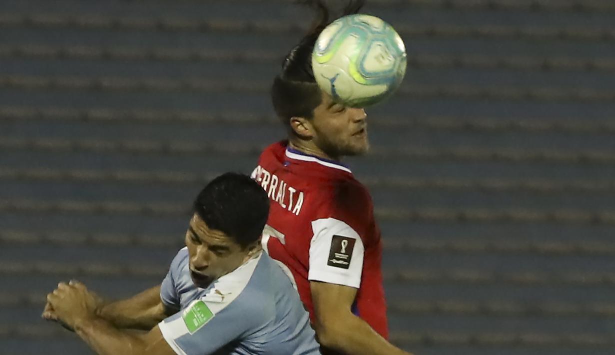 Penyerang Uruguay, Luis Suarez, berebut bola tas dengan bek Chile, Francisco Sierralta, pada laga kualifikasi Piala Dunia 2020 zona Amerika Selatan di Estadio Centenario, Jumat (9/10/2020) pagi WIB. Uruguay menang 2-1 atas Chile. (AFP/Raul Martinez/pool)