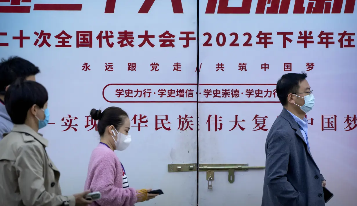 Orang-orang yang mengenakan masker melewati papan reklame yang menandai Kongres Nasional ke-20 Partai Komunis China yang akan datang, di Beijing, Selasa (11/10/2022). China adalah salah satu dari sedikit tempat di dunia yang masih menggunakan tindakan keras untuk mencegah penyebaran virus corona COVID-19. (AP Photo/Mark Schiefelbein)
