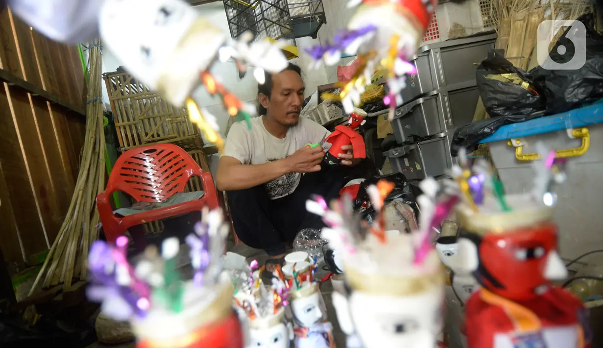 Pengrajin  menyelesaikan ondel-ondel hiasan yang terbuat dari limbah plastik botol di Kampung Sawah Lama, Ciputat, Tangerang Selatan, banten, Jumat (4/9/2020). Harga satu perpasang dijual dengan harga Rp 35 ribu, pada saat pandemi ini pemesanan menurut hingga 40 persen. (merdeka.com/Dwi Narwoko)