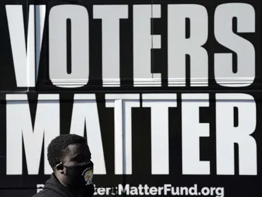 Seorang pria mengenakan masker saat berkumpul dengan sebuah kelompok untuk mendukung Black Voters Matter di tempat pemungutan suara Graham Civic Center, Graham, North Carolina, Amerika Serikat, Selasa (3/11/2020). (AP Photo/Gerry Broome)