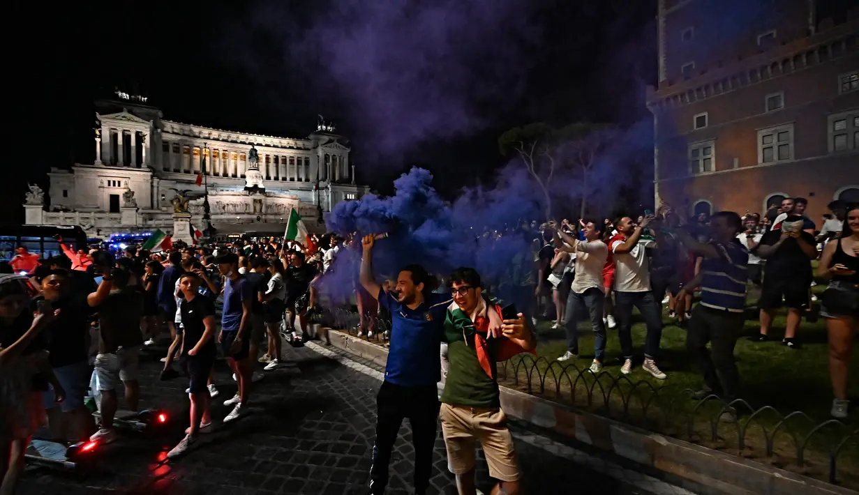 Suporter Italia merayakan kemenangan atas Spanyol pada pertandingan semifinal Euro 2020 di Piazza Venezia, di Roma tengah, Rabu (7/7/2021). Gli Azzurri berhak ke final Piala Eropa 2020. (AFP/Andreas Solaro)