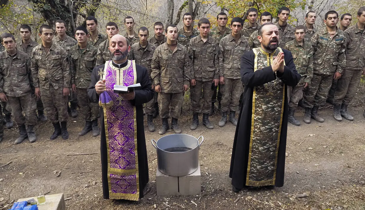 Pendeta Aristakes Hovhannisyan (kiri) dan Sebeos Galachyan melakukan upacara pembaptisan untuk tentara etnis Armenia di sebuah kamp militer dekat garis depan konflik di wilayah separatis Nagorno-Karabakh, Azerbaijan, Senin (2/11/2020). (AP Photo)