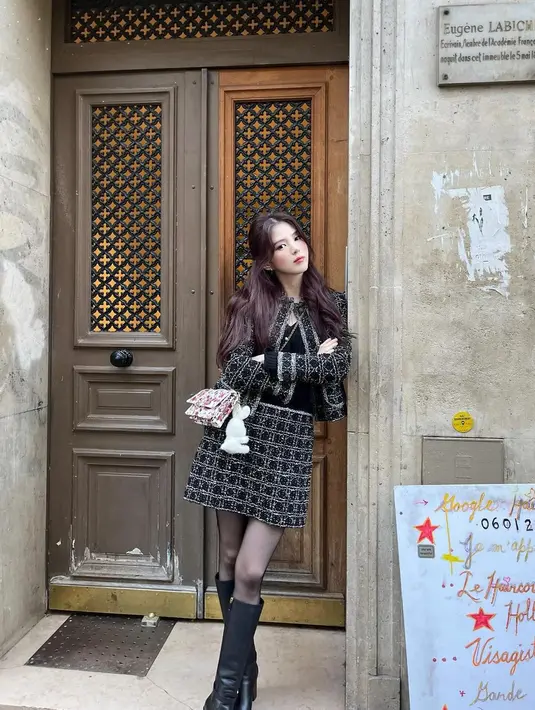 Manisnya Han So Hee dalam balutan outfit serba hitam. Ia mengenakan tank top yang ditumpuknya dengan setelan tweed blazer dan mini skirtnya. Han So Hee juga menambahkan sling bag pink, stoking hitam dan high boots yang juga berwarna hitam. [Foto: Instagram/xeesoxee]