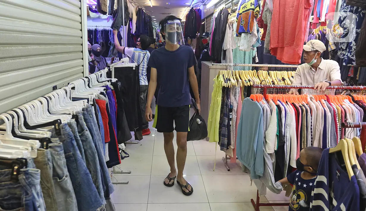 Seorang pria berjalan melewati kios pakaian bekas di Pasar Senen Blok III, Jakarta, Kamis (11/6/2020). Pasar yang tetap buka saat PSBB dengan pembatasan jam operasional ini akan kembali dibuka secara normal pada 15 Juni 2020 dengan aturan protokol kesehatan COVID-19. (Liputan6.com/Herman Zakharia)